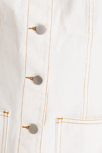 Closeup image of a model wearing a trendy white mini denim dress from Boho Bum Island Boutique.