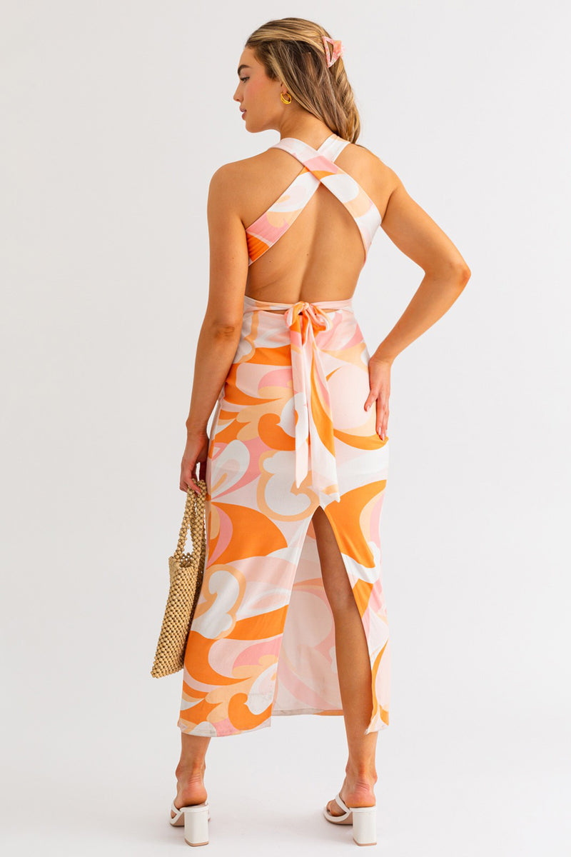 Model wearing a halter neck cross back midi summer dress in orange and white multicolor from Boho Bum Island Boutique