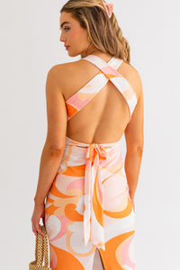 Model wearing a halter neck cross back midi summer dress in orange and white multicolor from Boho Bum Island Boutique
