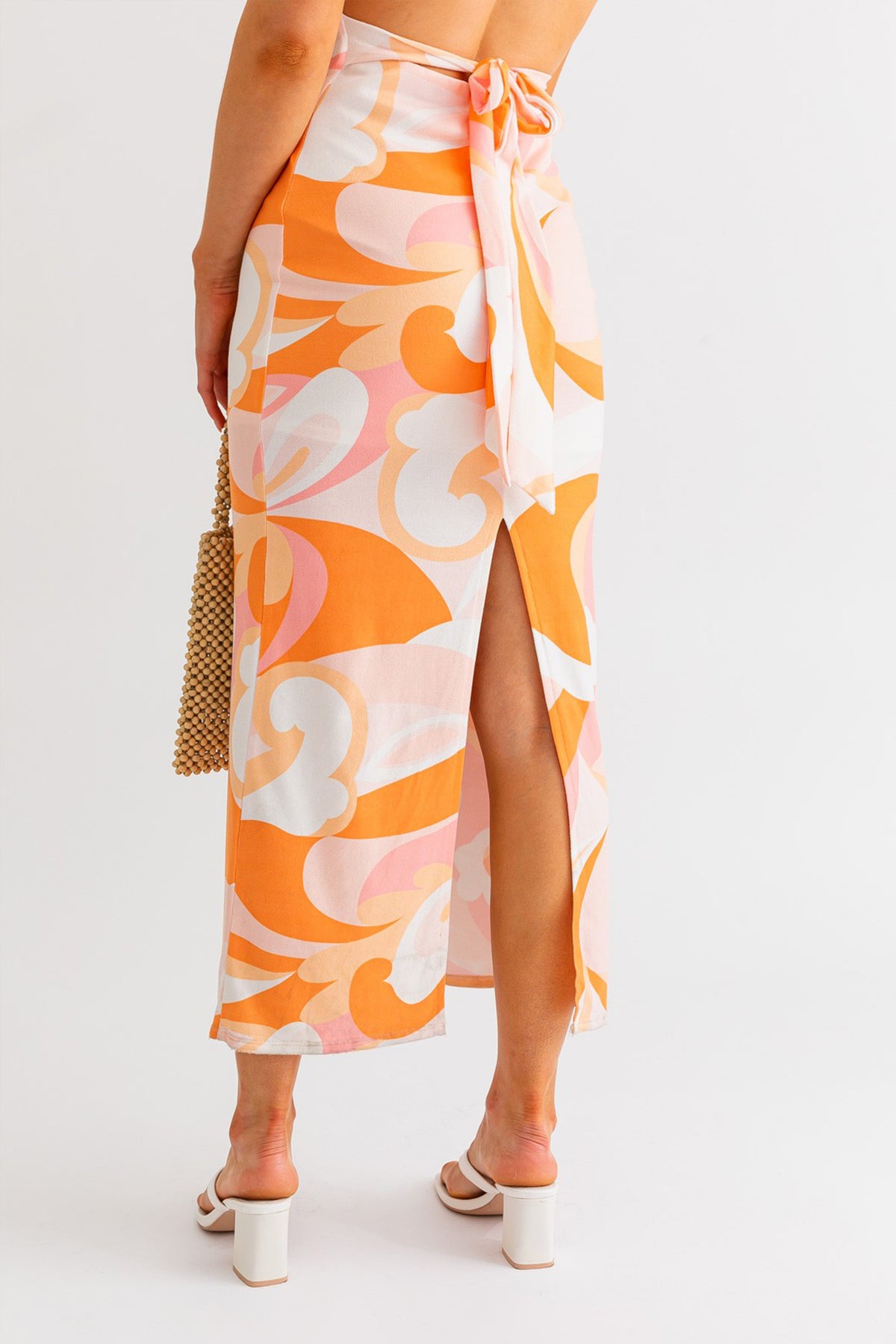Model wearing a halter neck cross back midi summer dress in orange and white multicolor from Boho Bum Island Boutique