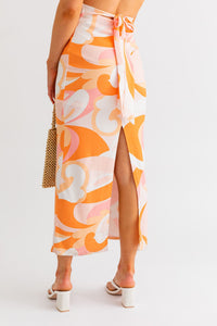 Model wearing a halter neck cross back midi summer dress in orange and white multicolor from Boho Bum Island Boutique